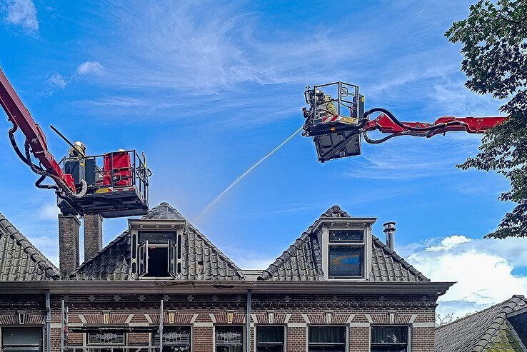 Brandweerlieden blussen vanuit hoogwerkers de brand in de Kamper binnenstad. - Foto: Hardo Junte